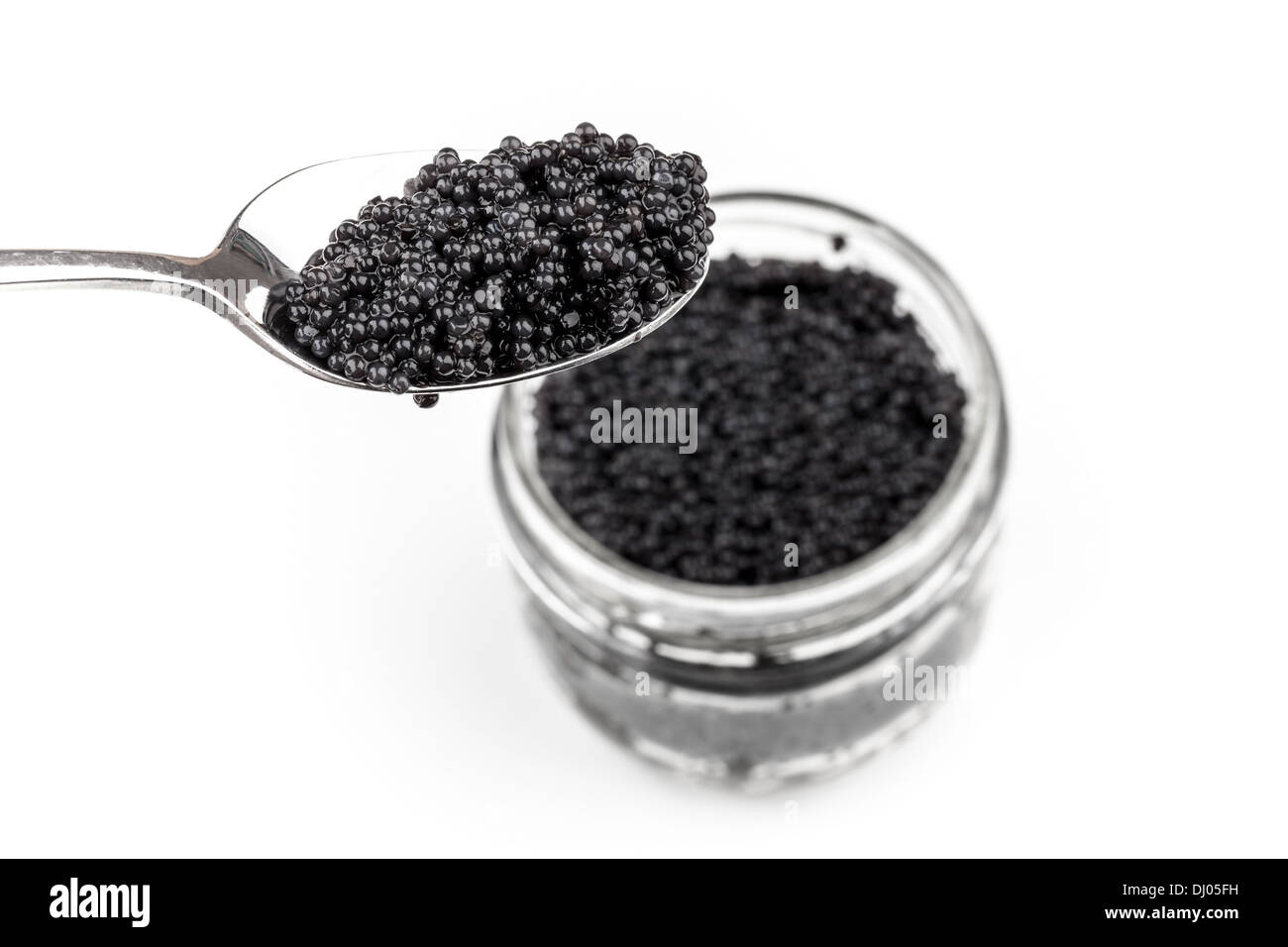 Black caviar in full glass jar and teaspoon isolated on white background Stock Photo