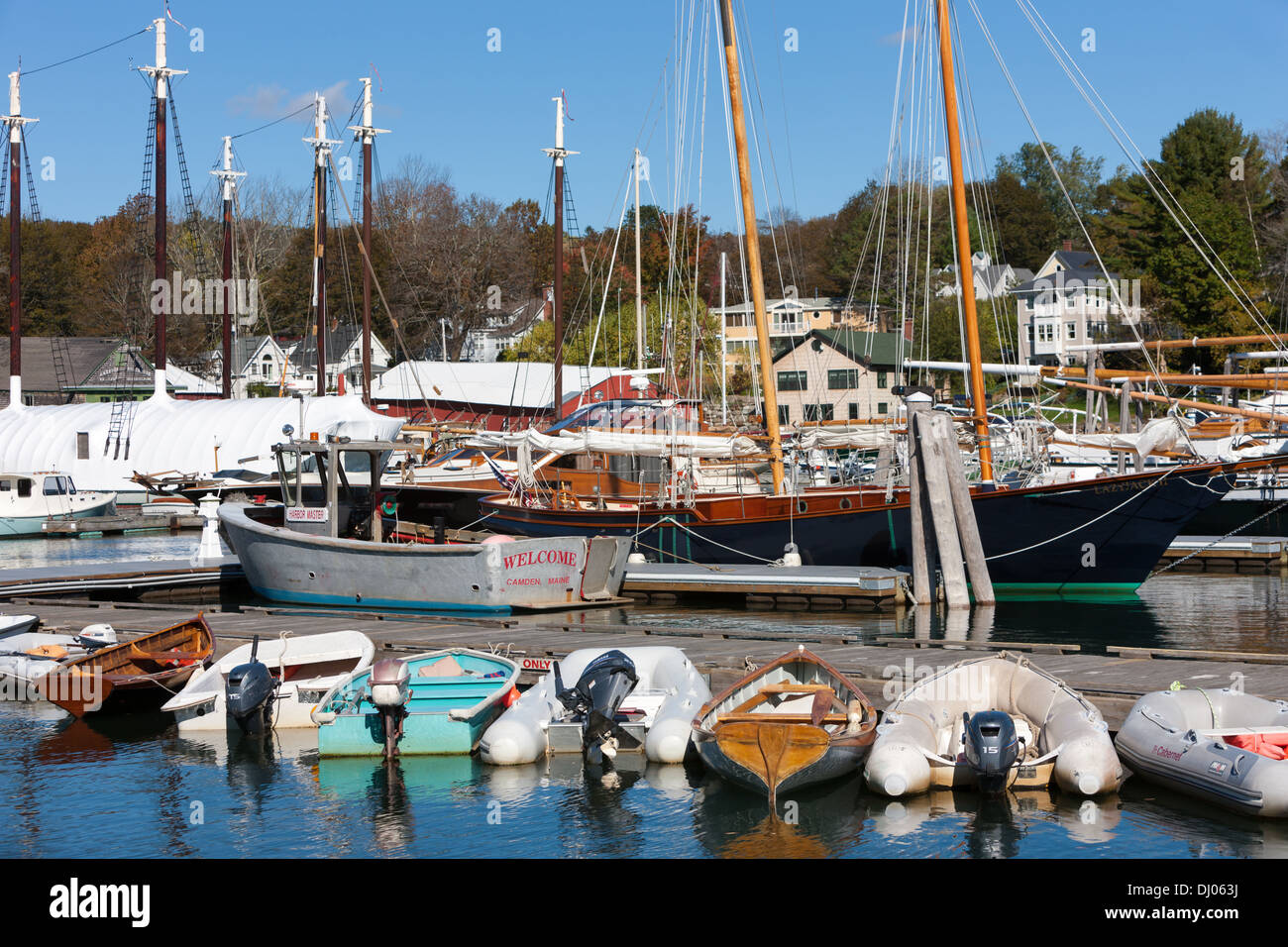 Dinghies line a dock in front of schooners and windjammers anchored in Camden harbor in Camden, Maine. Stock Photo