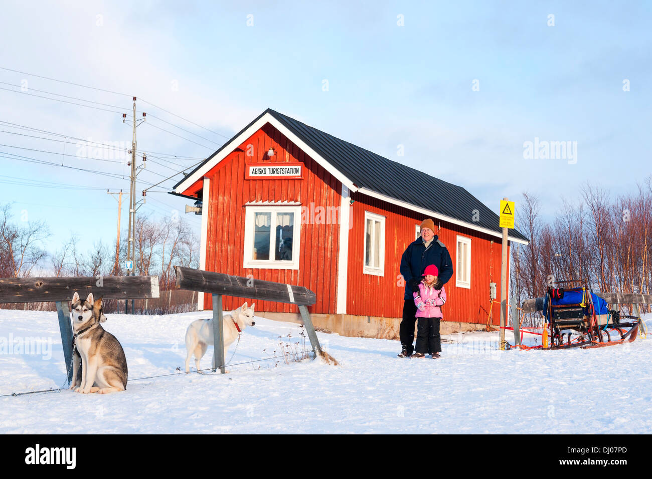 Man and child watching sled dogs outside the Abisko train station in arctic Sweden Stock Photo