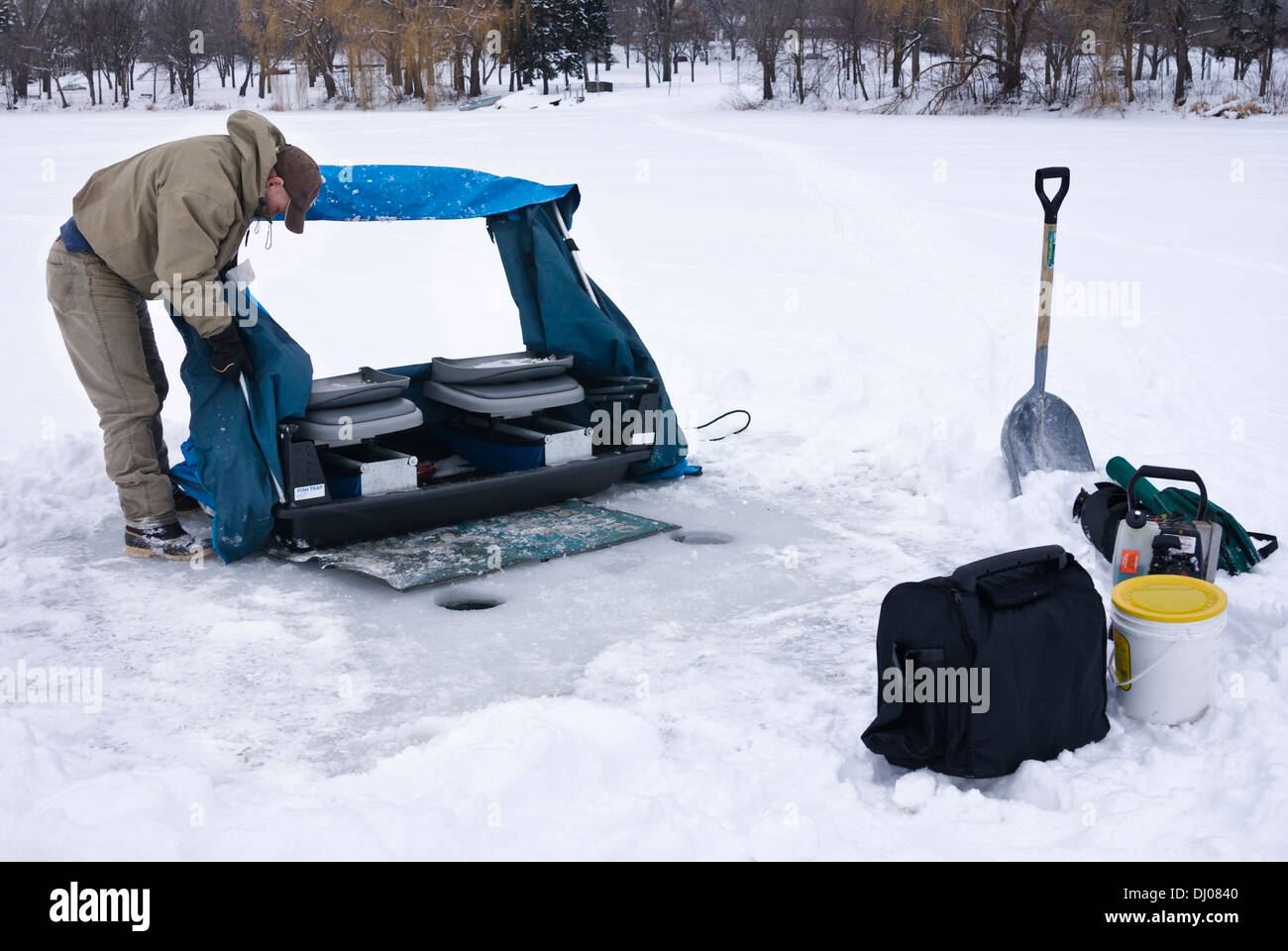 Man breaks down his temporary ice fishing shack on a frozen lake