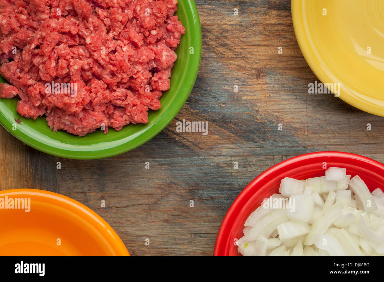 low cholesterol, grass fed, ground buffalo meat and diced onion in colorful ceramic bowls on wood cutting board Stock Photo