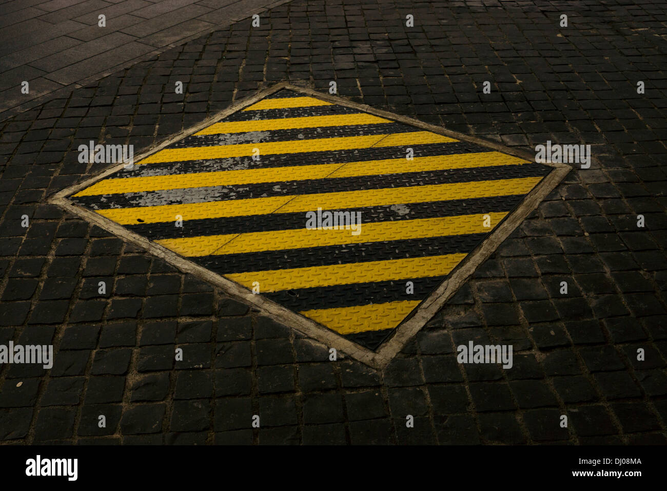 black yellow strips metal cover stone cobbed floor Stock Photo