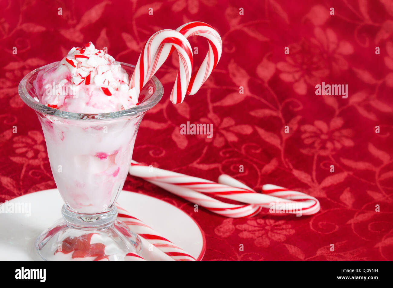 Peppermint ice cream with candy canes on red holiday background Stock