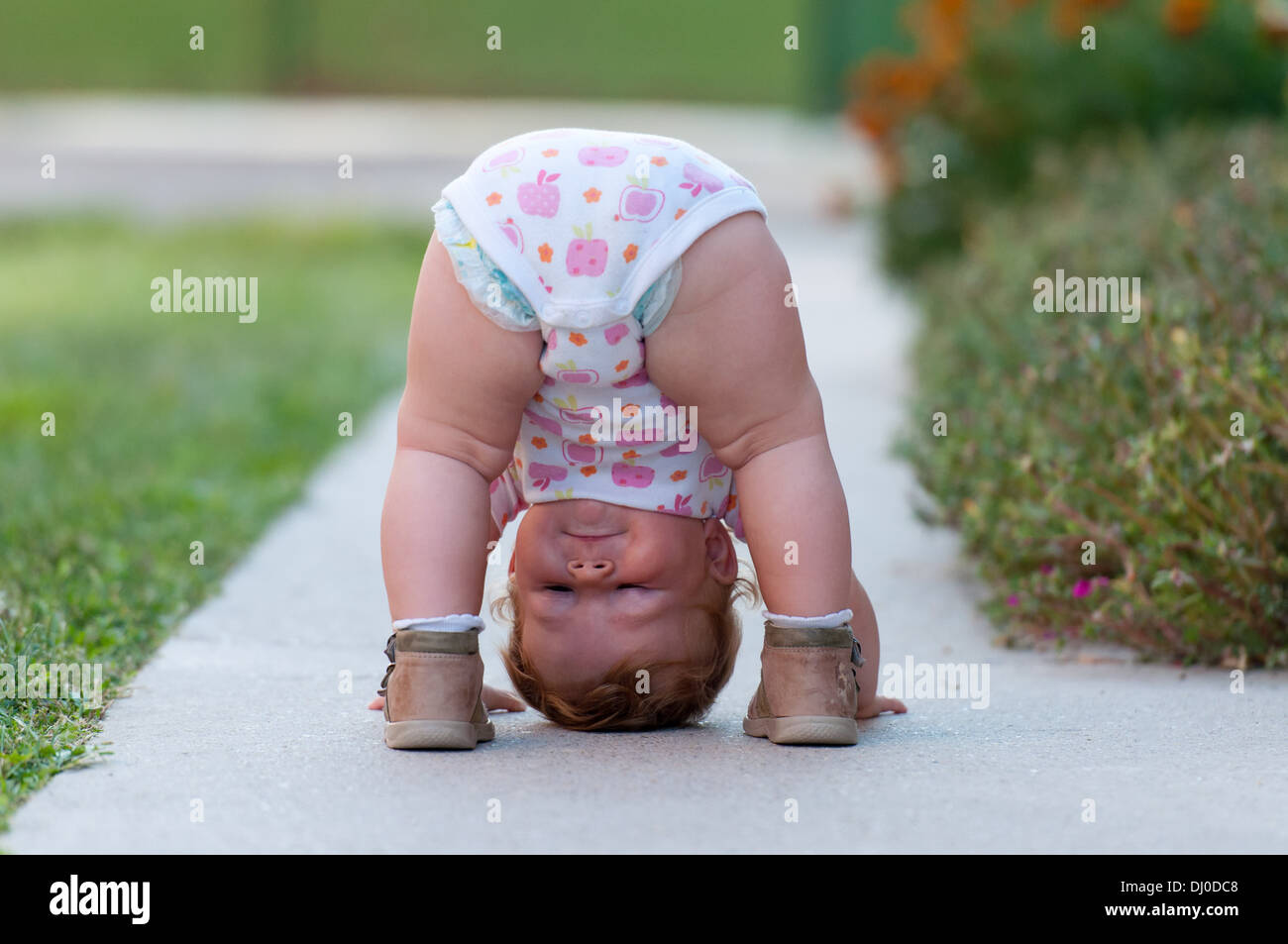 Oneyear baby girl playing upside down on the street Stock Photo Alamy