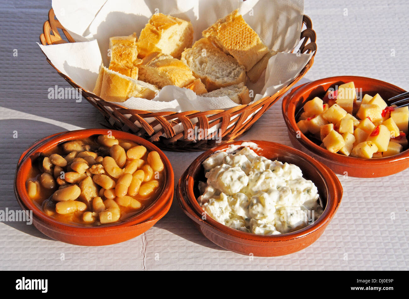 Selection of tapas - From left to right: White beans and pork (Alubias con Morro), Potato salad, Cubed Manchego cheese in oil. Stock Photo