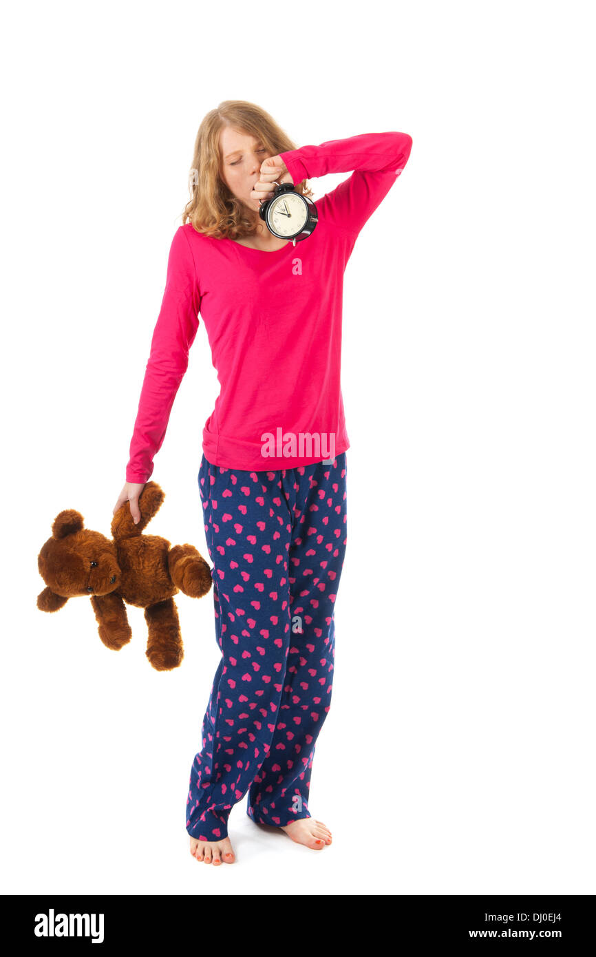 Young girl is going to bed with toy bear and alarm clock Stock Photo