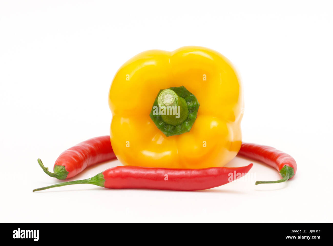 Yellow pepper with three red chili peppers on a white background Stock Photo