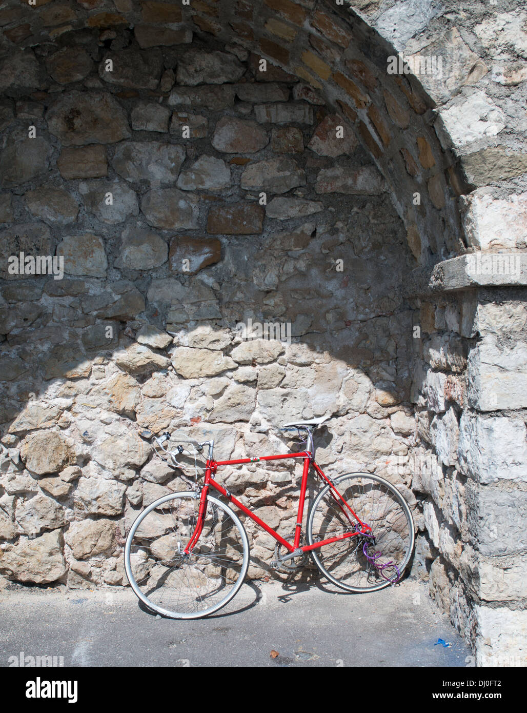 Red racing bicycle parked within a stone arch within the French town of Antibes, Europe Stock Photo