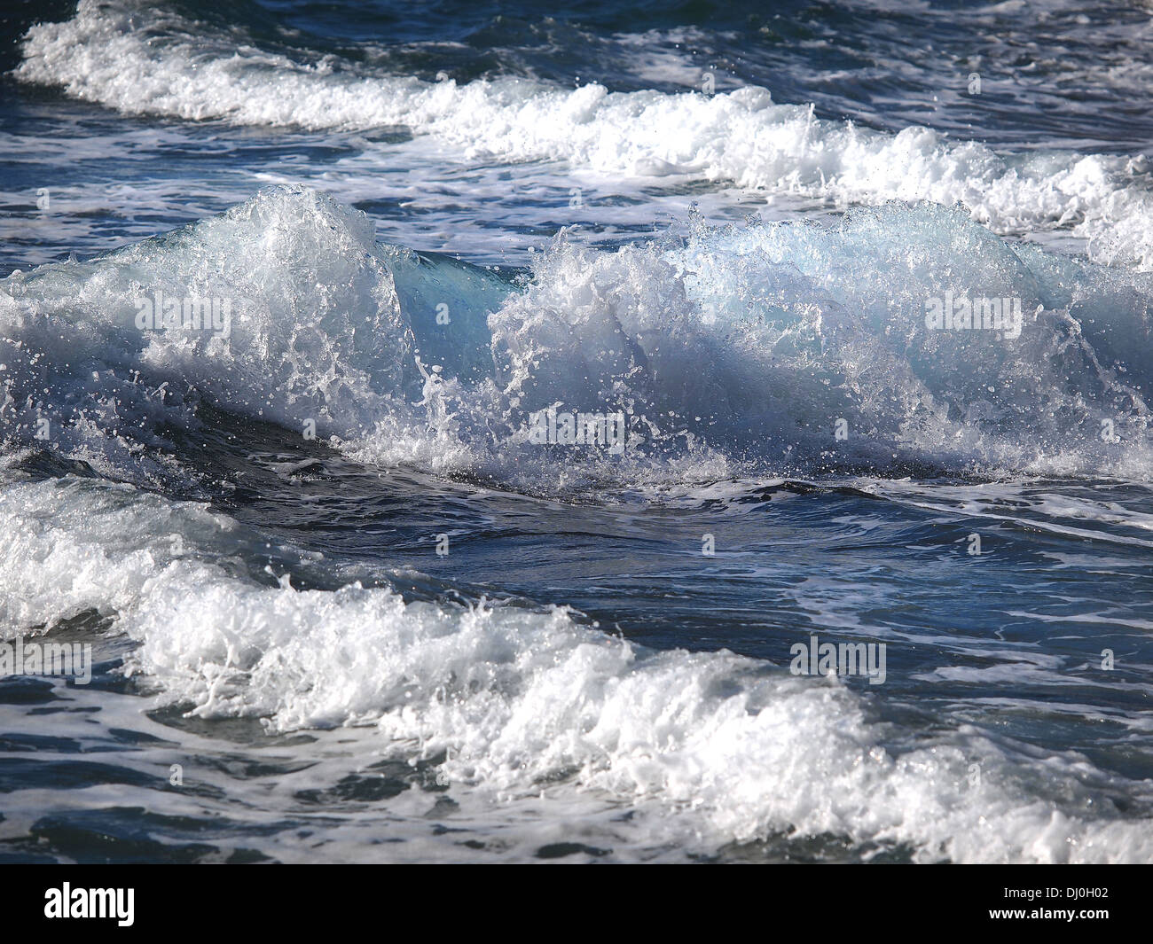 Turquoise rolling wave slamming on the rocks of the coastline  Stock Photo