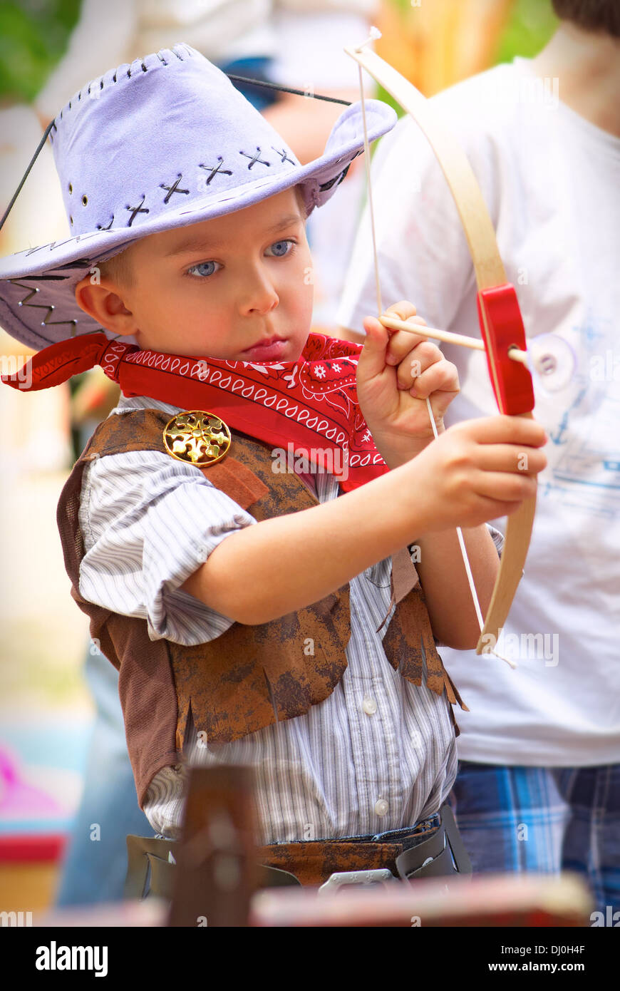 Little cowboy shoots a bow with serious calm gaze Stock Photo