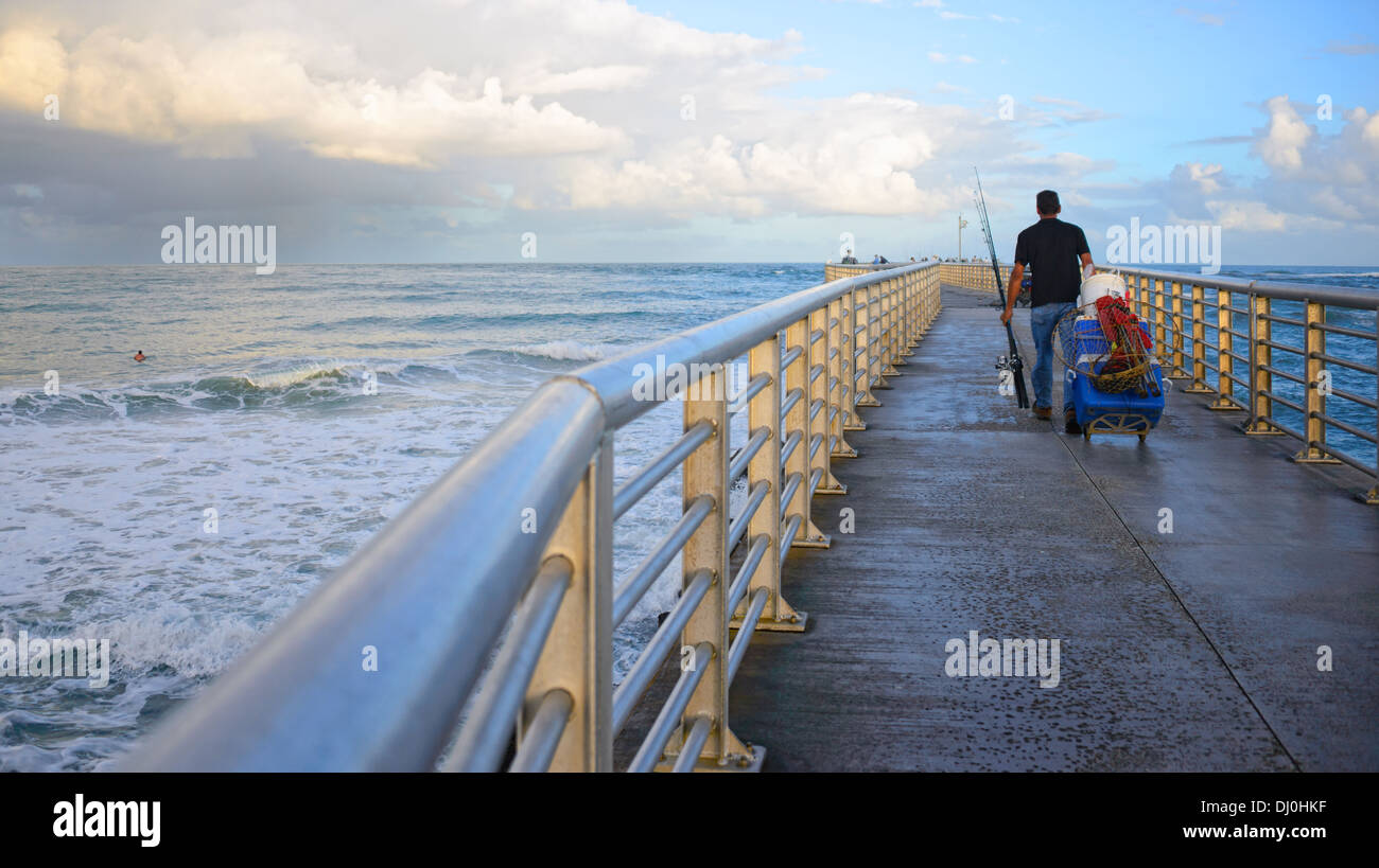 Fisherman rolls his equipment out on the Sebastian Inlet fishing jetty for an evening of fishing. Stock Photo