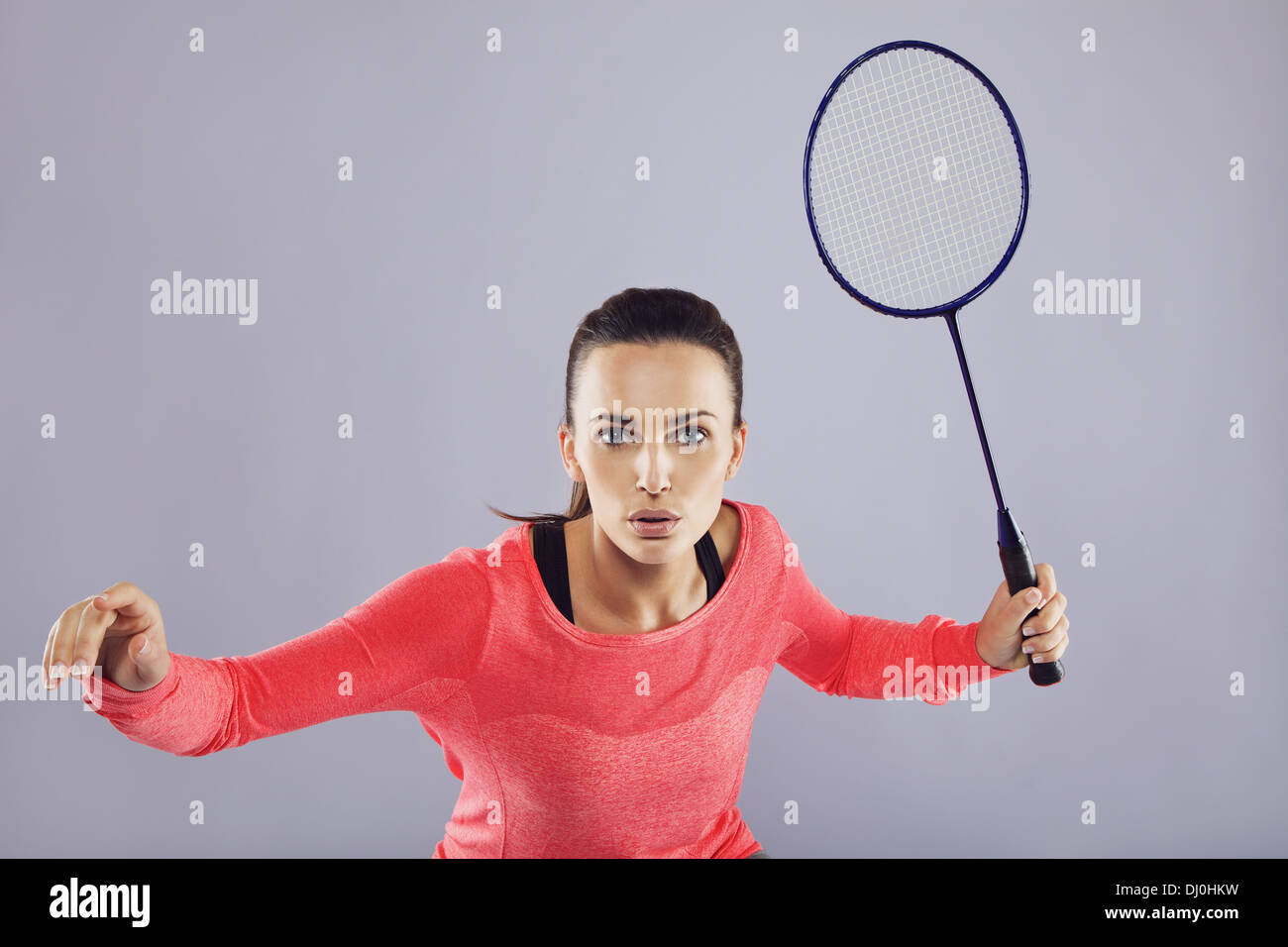 Portrait of young sports woman playing badminton against grey background. Fit athlete playing badminton. Stock Photo