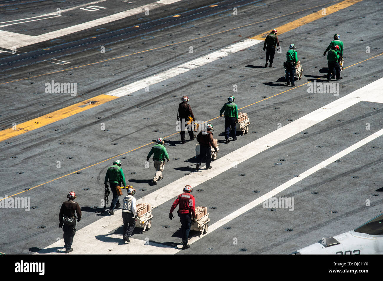 Sailors from the aircraft carrier USS George Washington (CVN 73) prepare to load containers of fresh water onto an MH-60R Seahawk helicopter from the Saberhawks of Helicopter Maritime Strike Squadron (HSM) 77 to be delivered ashore in support of Operation Stock Photo
