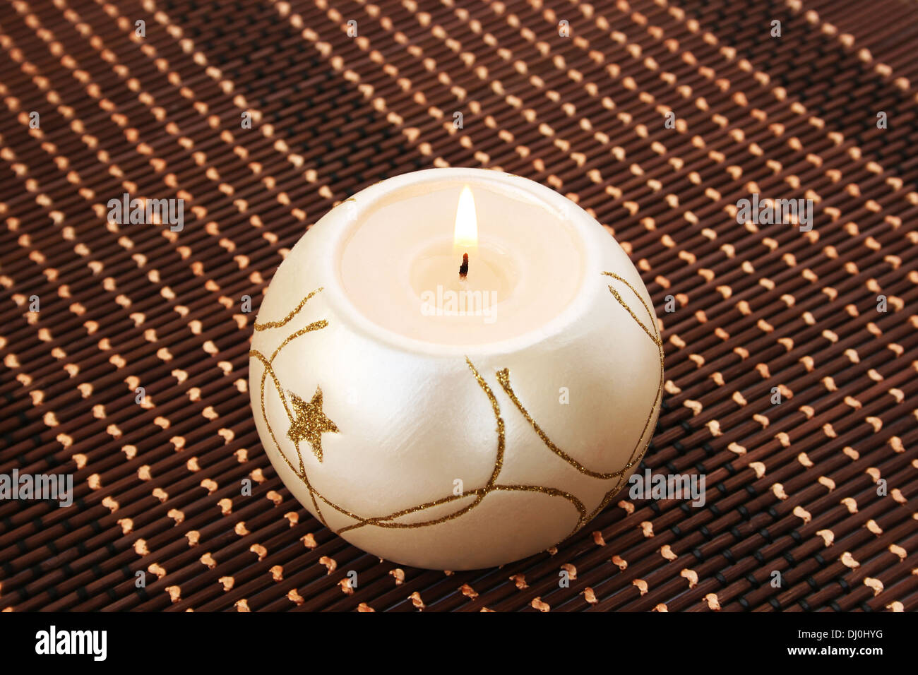 Burning candle isolated on bamboo background. Stock Photo