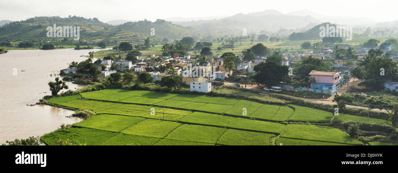 Hazy misty sunny morning over a rural south indian village next to lake. Andhra Pradesh, India. Panoramic Stock Photo