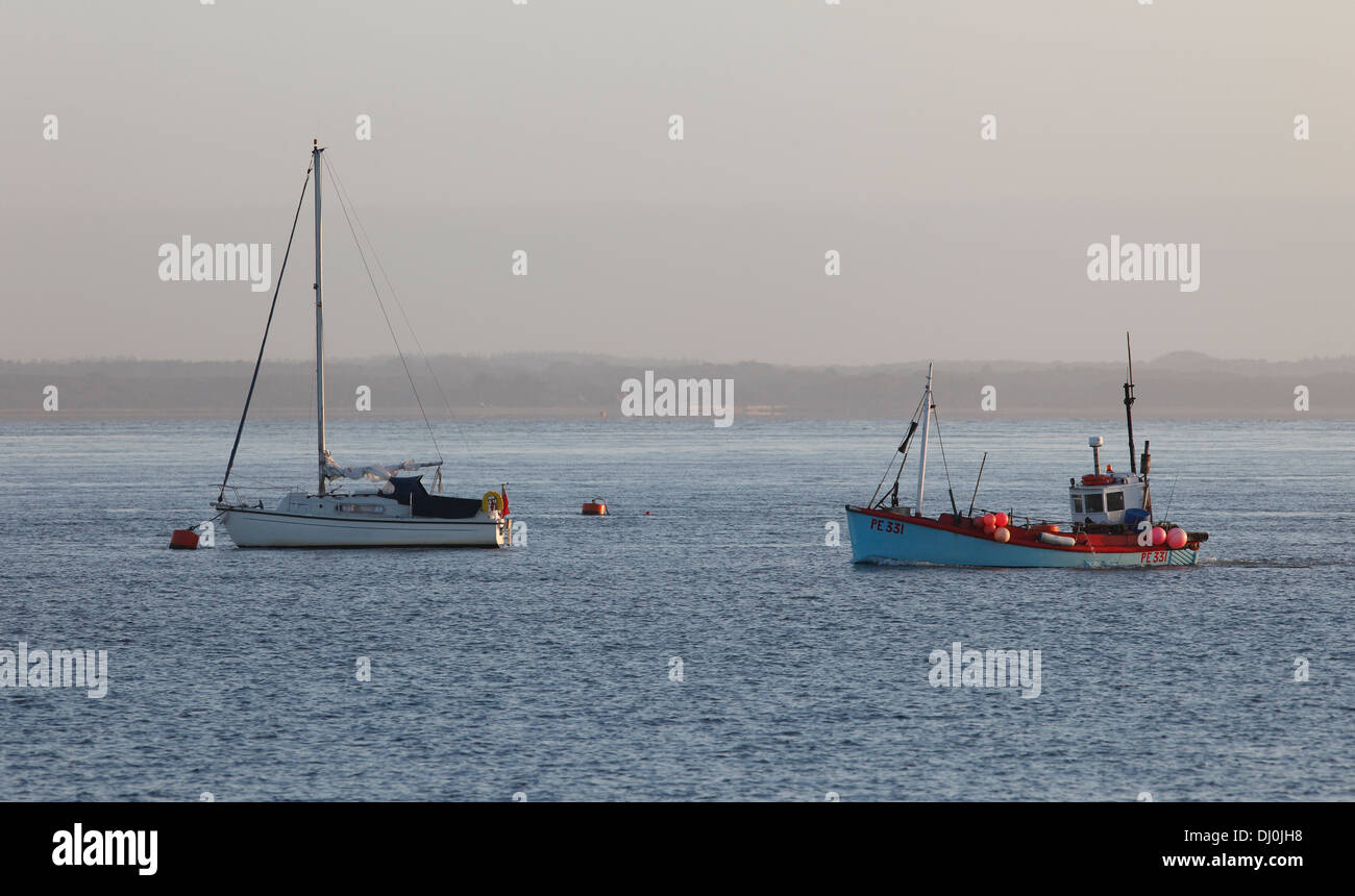 Fishing vessel passing moored yacht on Solent Isle of Wight Hampshire England Stock Photo