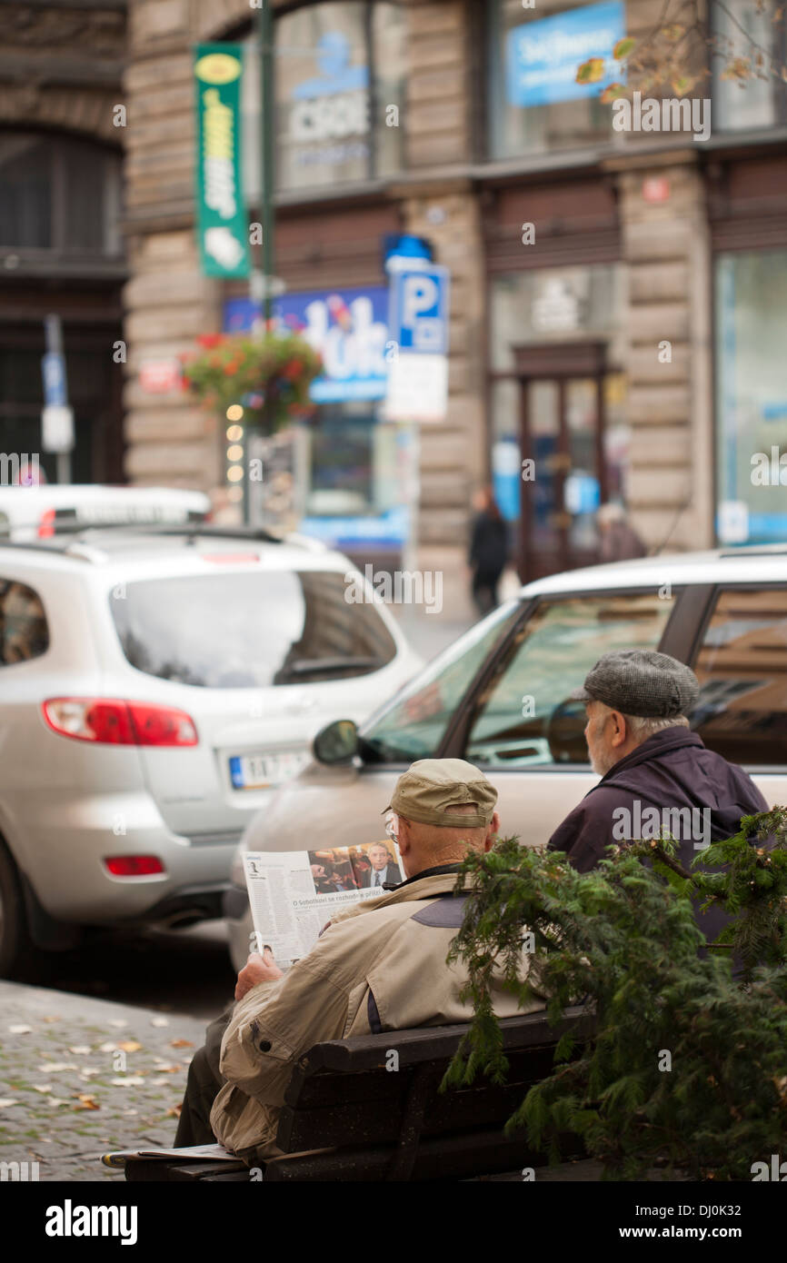Two old men sitting on a bench and reading newspaper. Prague. Stock Photo