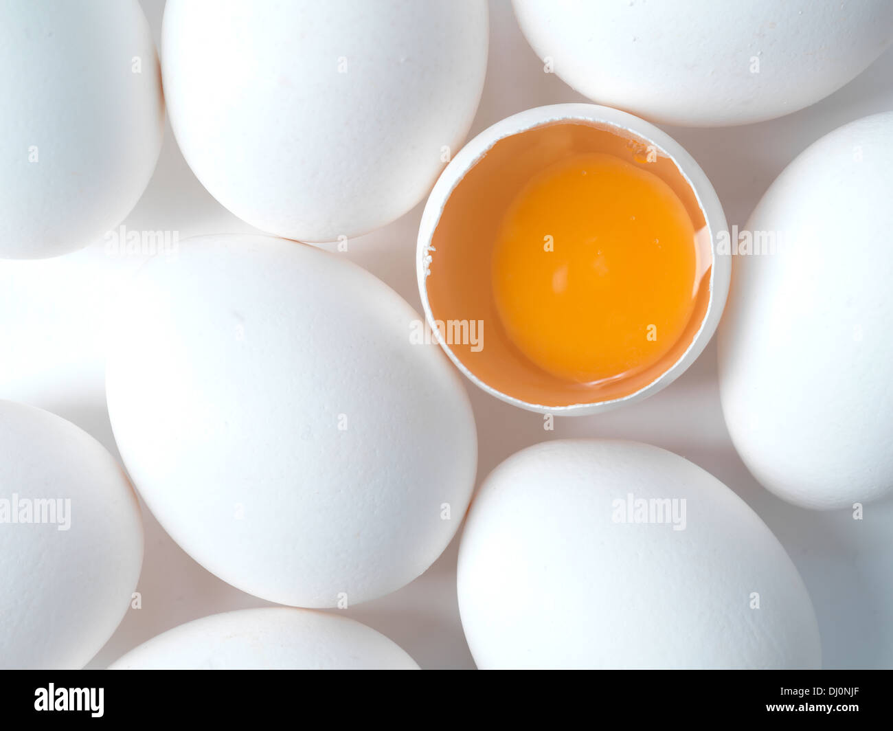white chicken eggs shot from above, one open egg showing yolk Stock