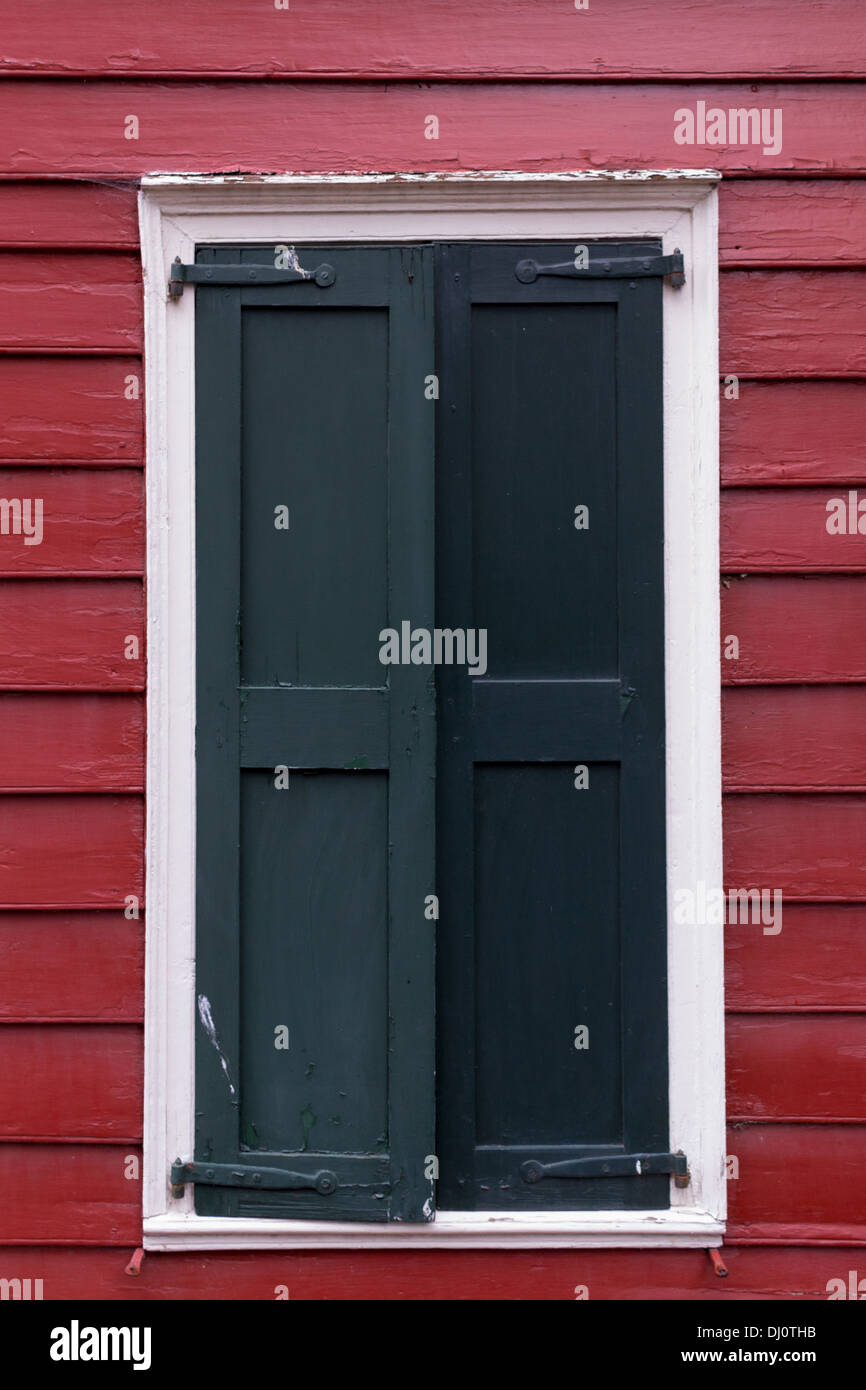 Old Black Shutters against red siding Stock Photo