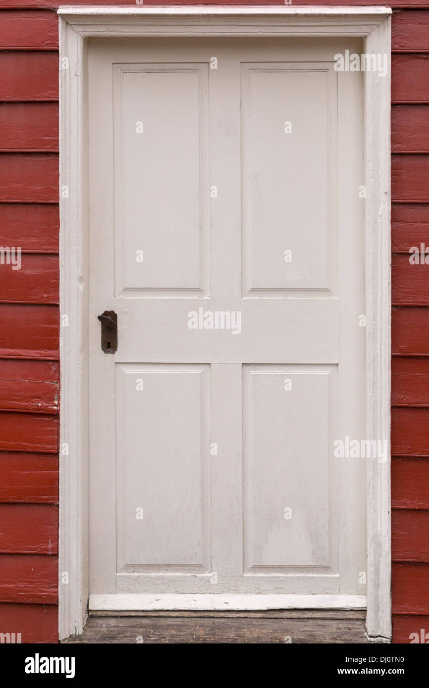 Old White Door set in red clapboard siding Stock Photo