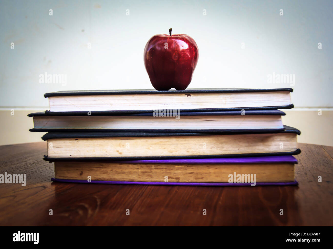 withered red apple and old books on wooden tabletop. Stock Photo