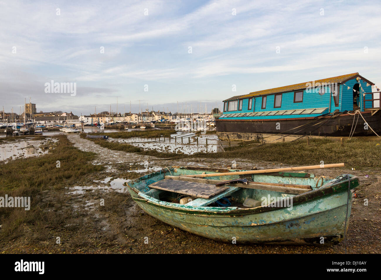 A house boat and a rowing boat are on the shore opposite Shorehamby