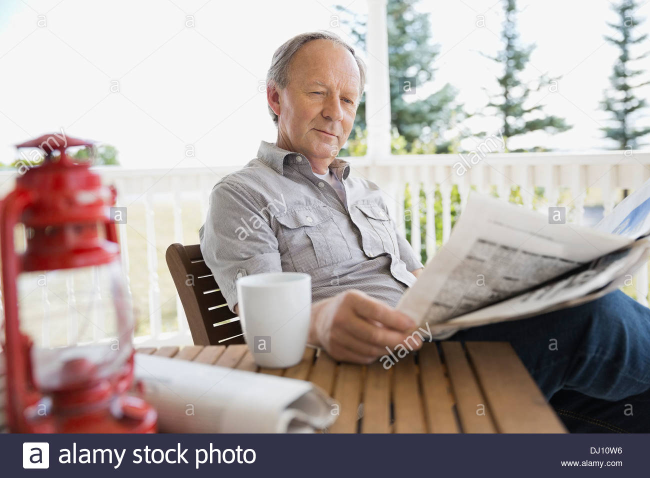 Senior man reading newspaper on porch Stock Photo