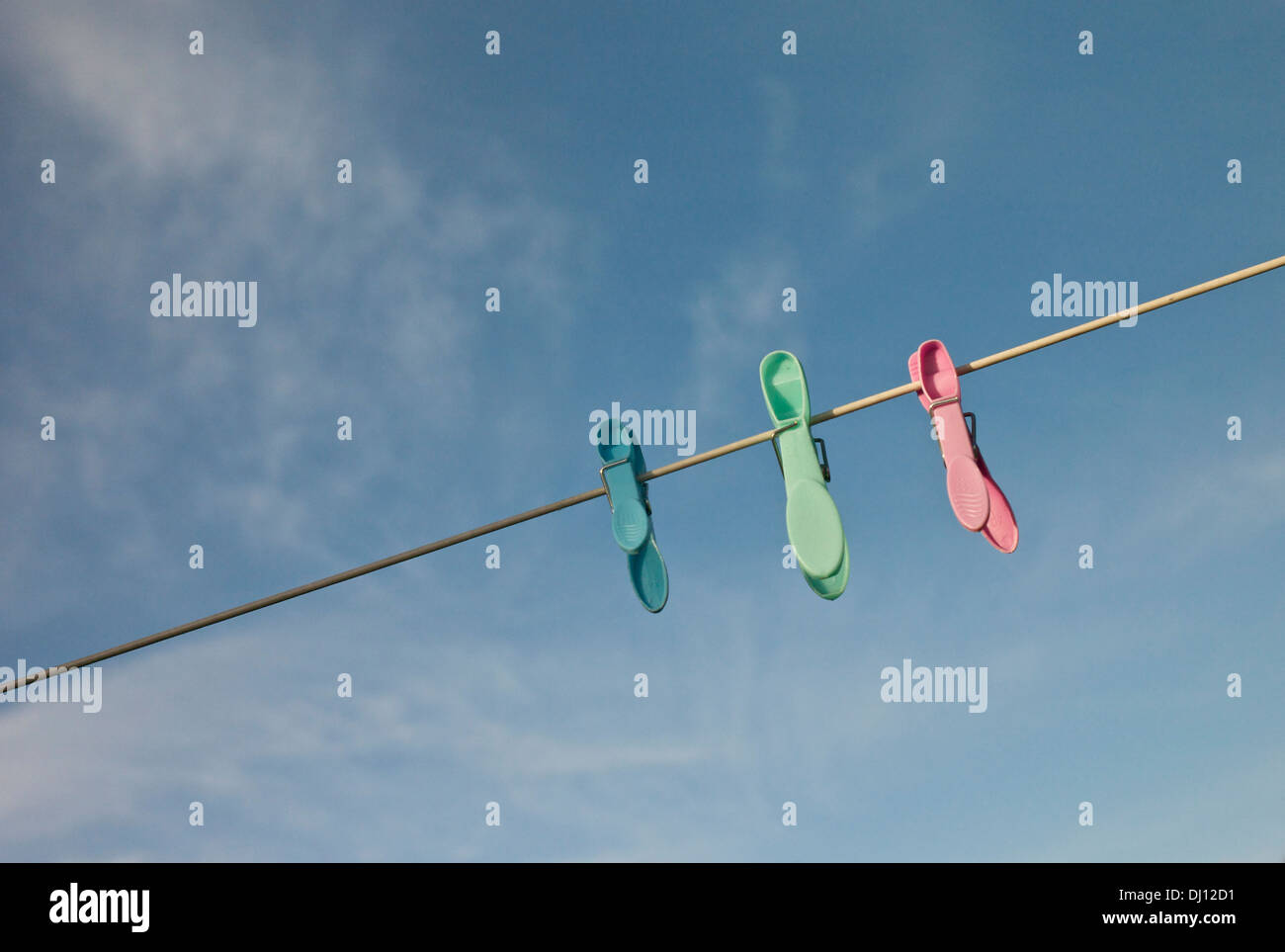 Three plastic clothes pegs on a washing line. Stock Photo