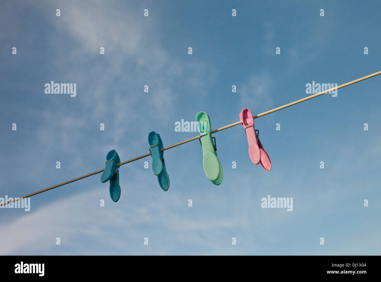 Four plastic clothes pegs on a washing line. Stock Photo