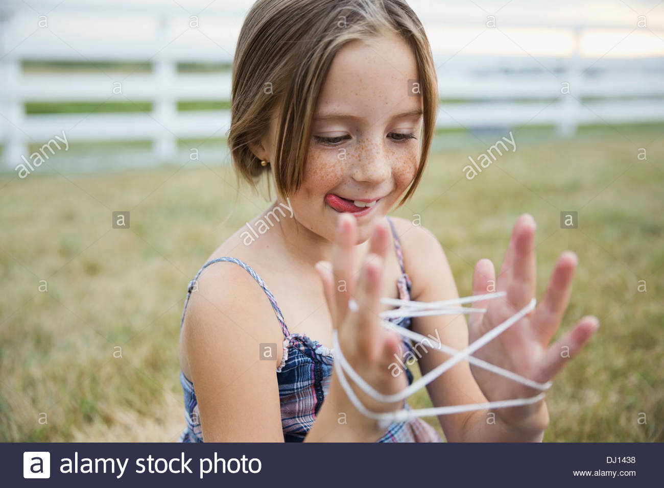Young girl playing cats cradle outdoors Stock Photo