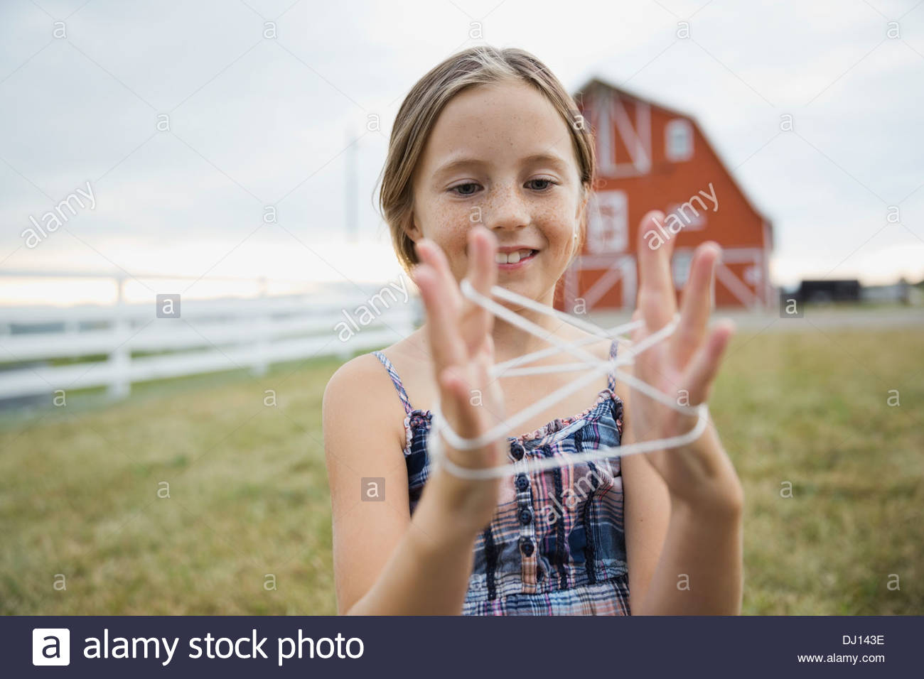 Young girl playing cats cradle on farm Stock Photo