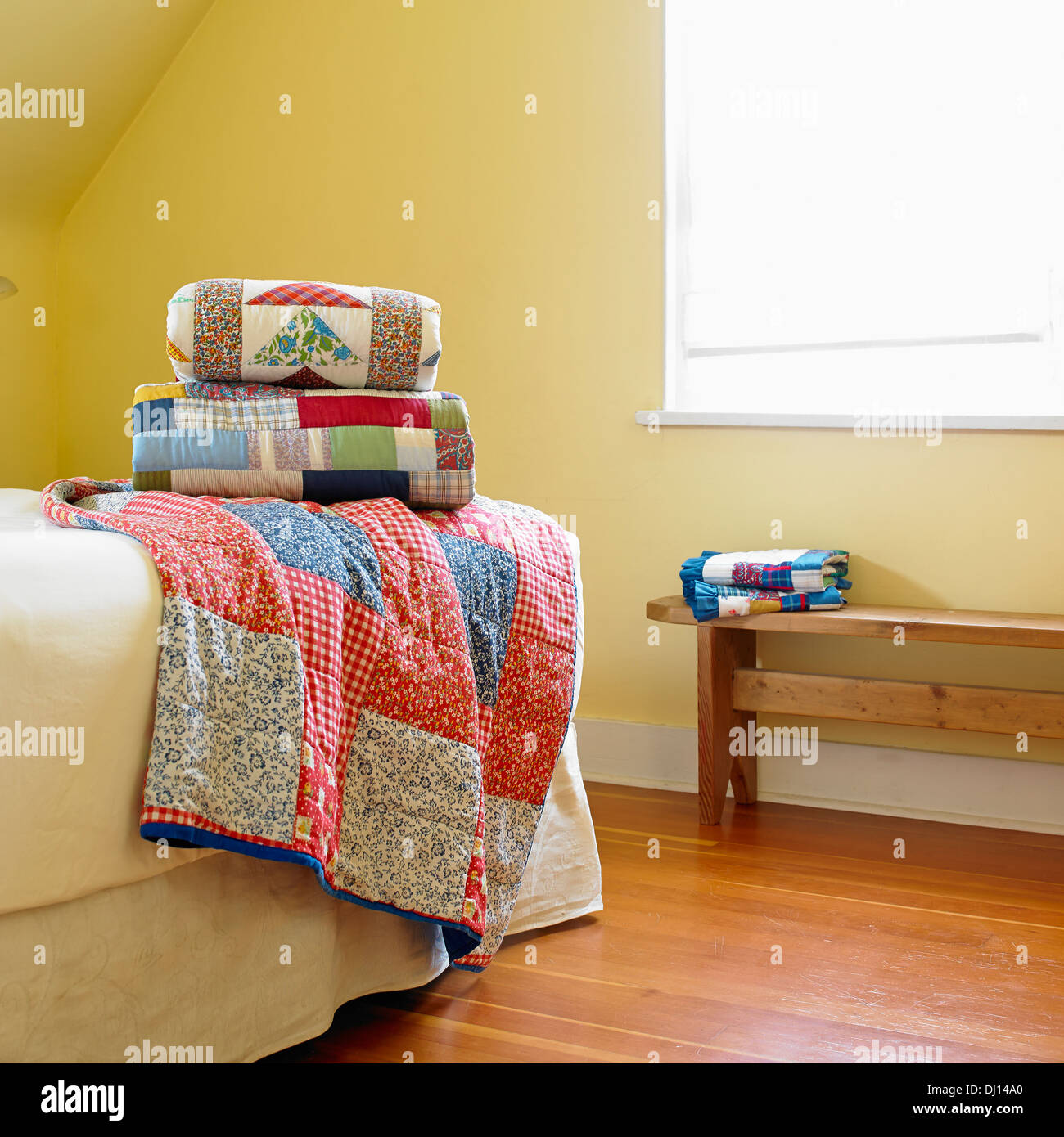 Traditional Quilts Stacked On A Bed In A Yellow Room; Victoria