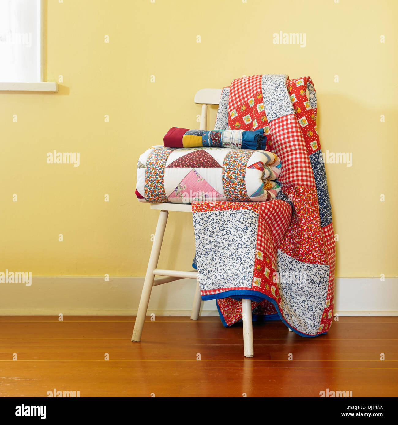 Traditional Quilts Stacked On A Chair In A Yellow Room; Victoria