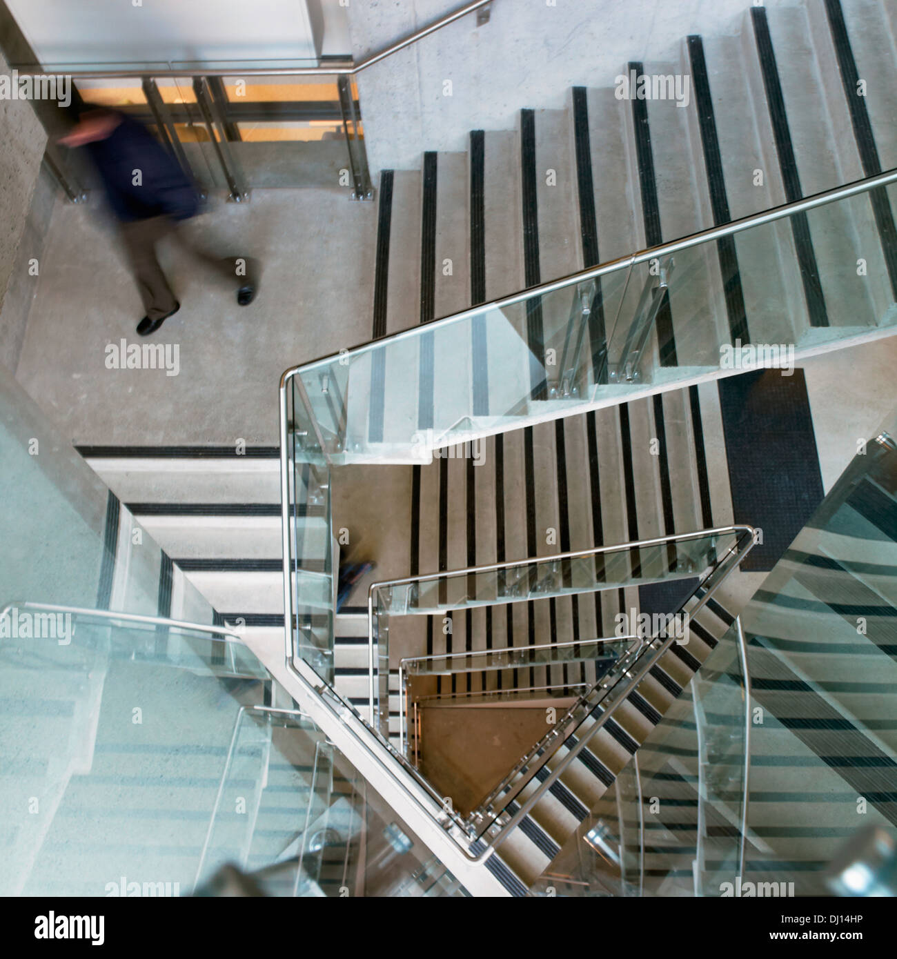 Person Walking Down Staircase In A Glass Building Stock Photo