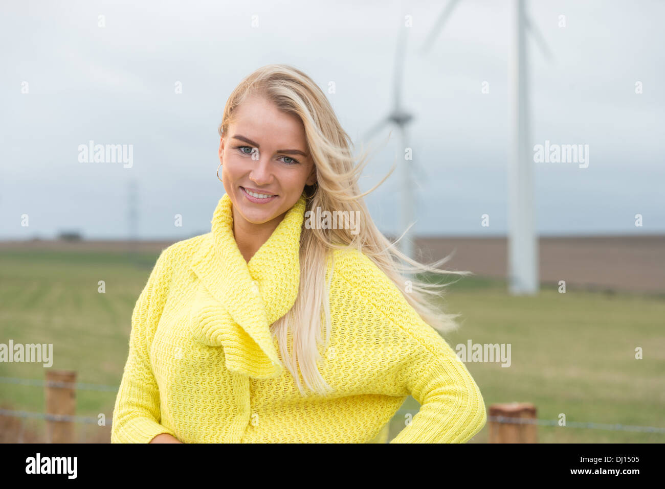 Attrictive blonde haired woman in the countryside with a windfarm in the background Stock Photo