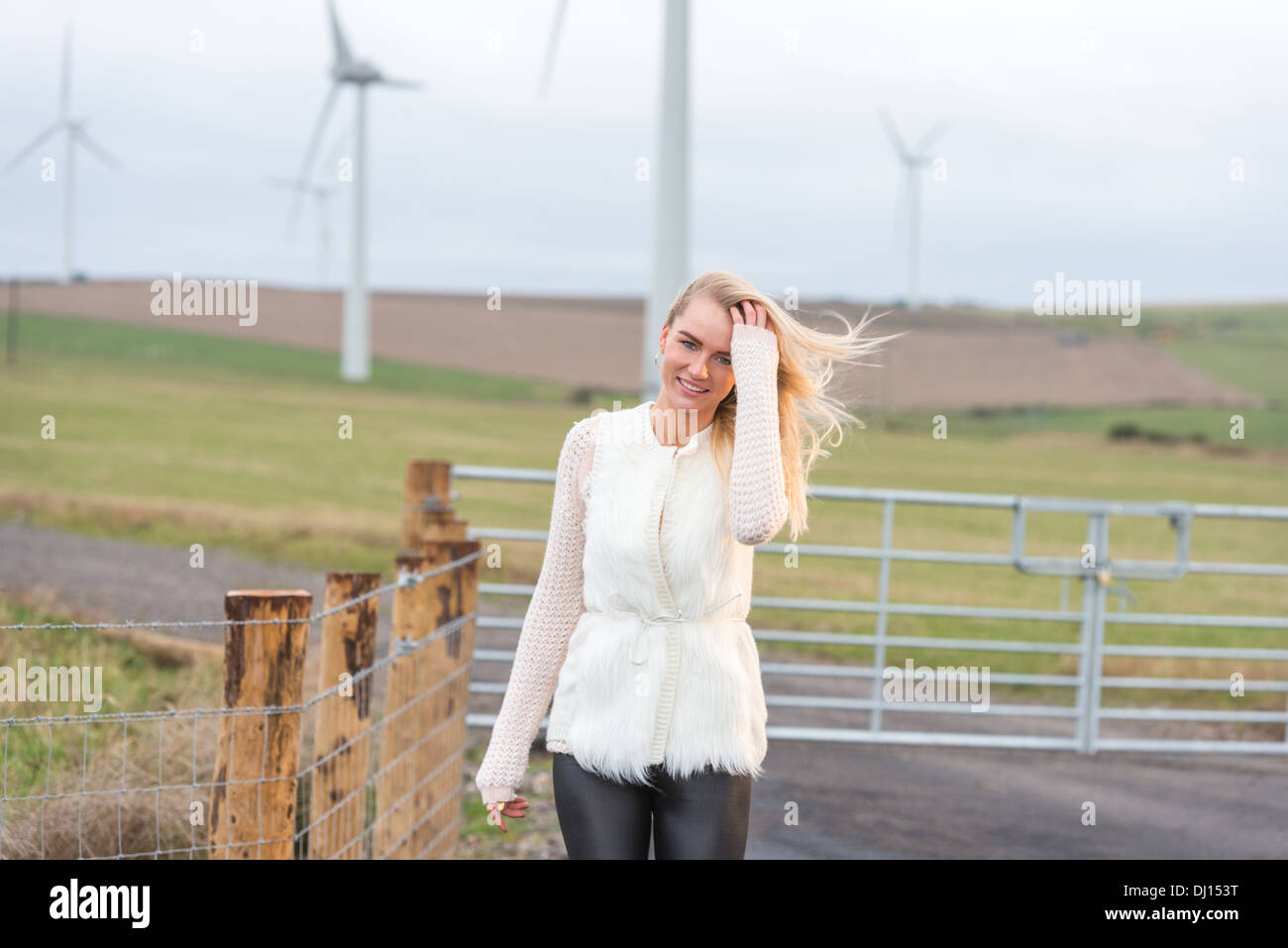 Attrictive blonde haired woman in the countryside with a windfarm in the background Stock Photo