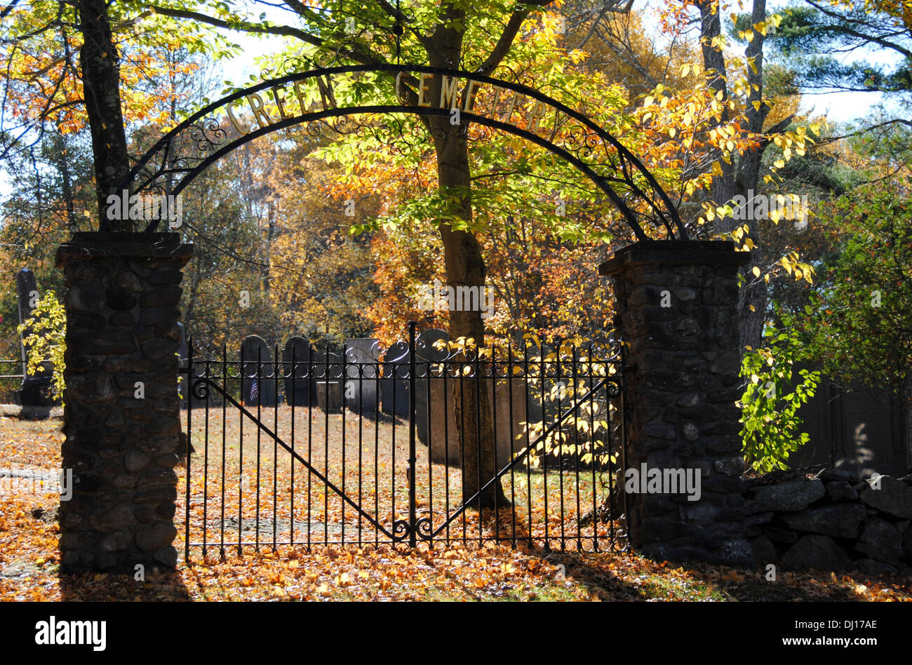 Black and gold iron cemetery gate with autumn color in the afternoon light, Green cemetery, Carlisle, MA. Stock Photo