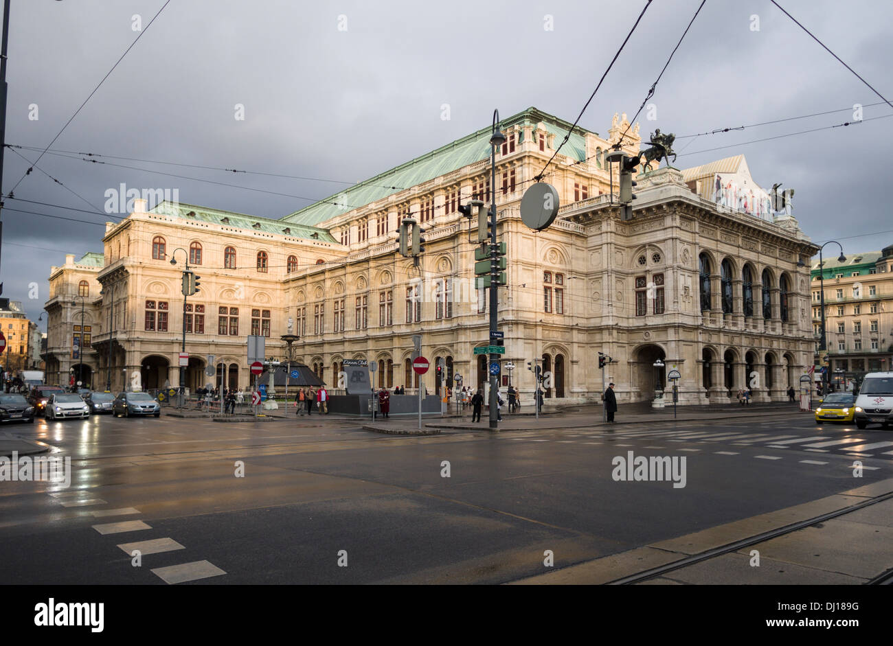 Vienna Opera House and the Ringstrasse at sunset. A damp road highlights the massive stone building. Stock Photo