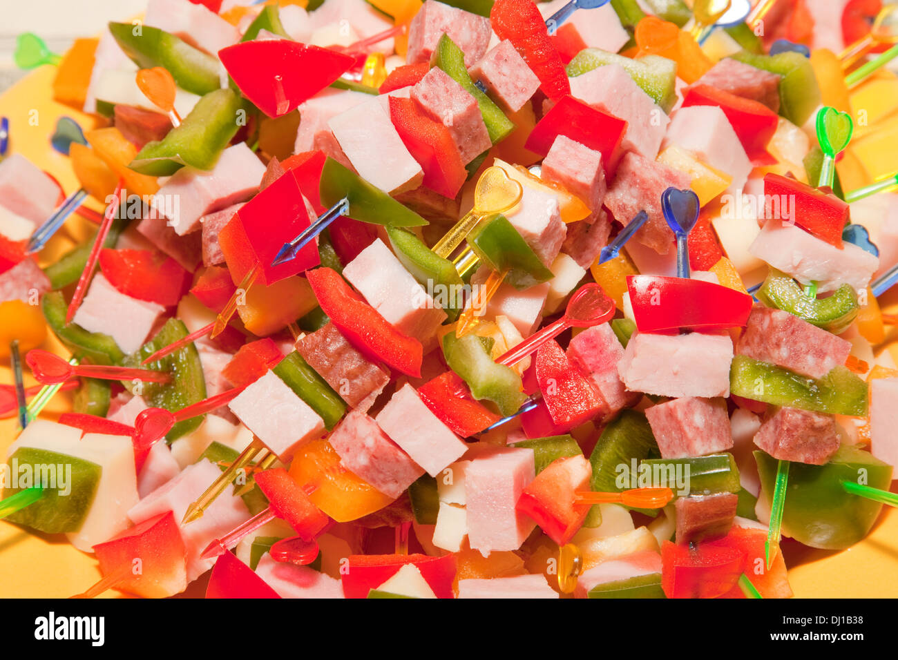 Party food, ham, salami cheese and vegetables on plastic sticks Stock