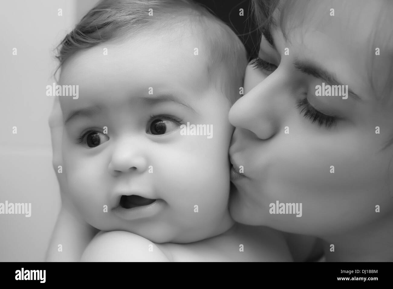 Mother giving a kiss to her little happy baby baby boy; black and white Stock Photo