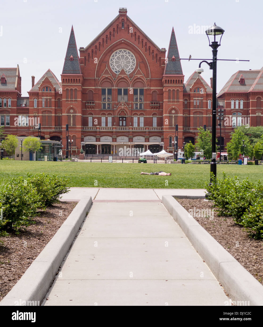 Cincinnati Music Hall with Sunbather. A young man catches a few spring rays on the lawn in front of the red brick music hall. Stock Photo