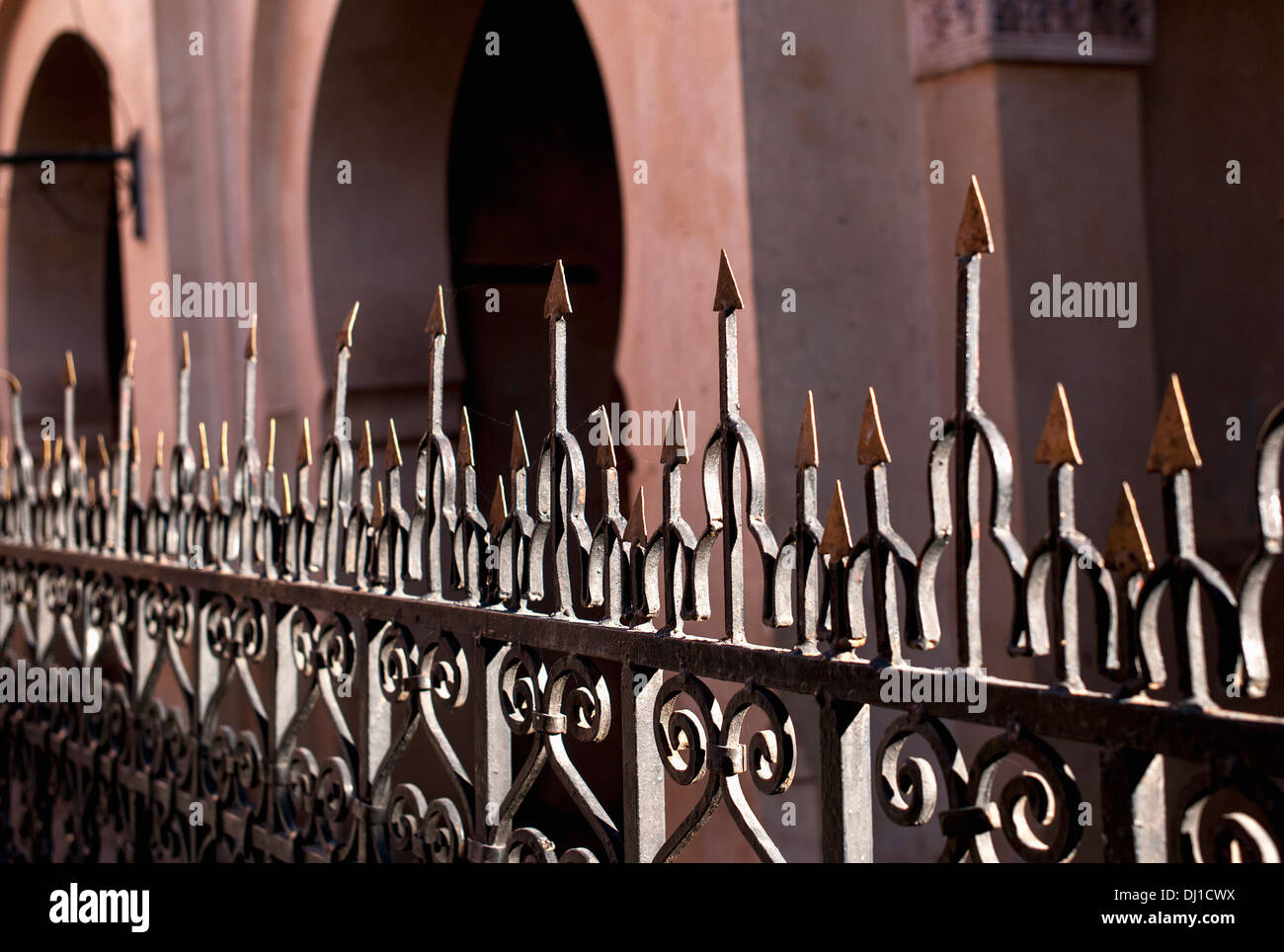 A Metal Railing With Sharp Pointed Edges On Top And A Building With Arched Doorways Stock Photo