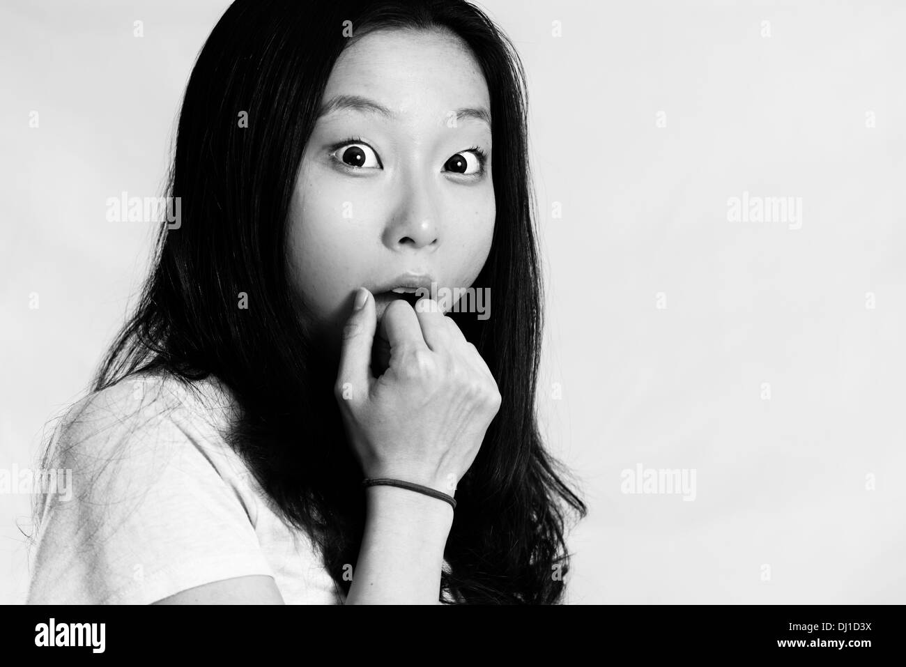 Portrait of young woman looking shocked and covering her mouth, black and white style Stock Photo