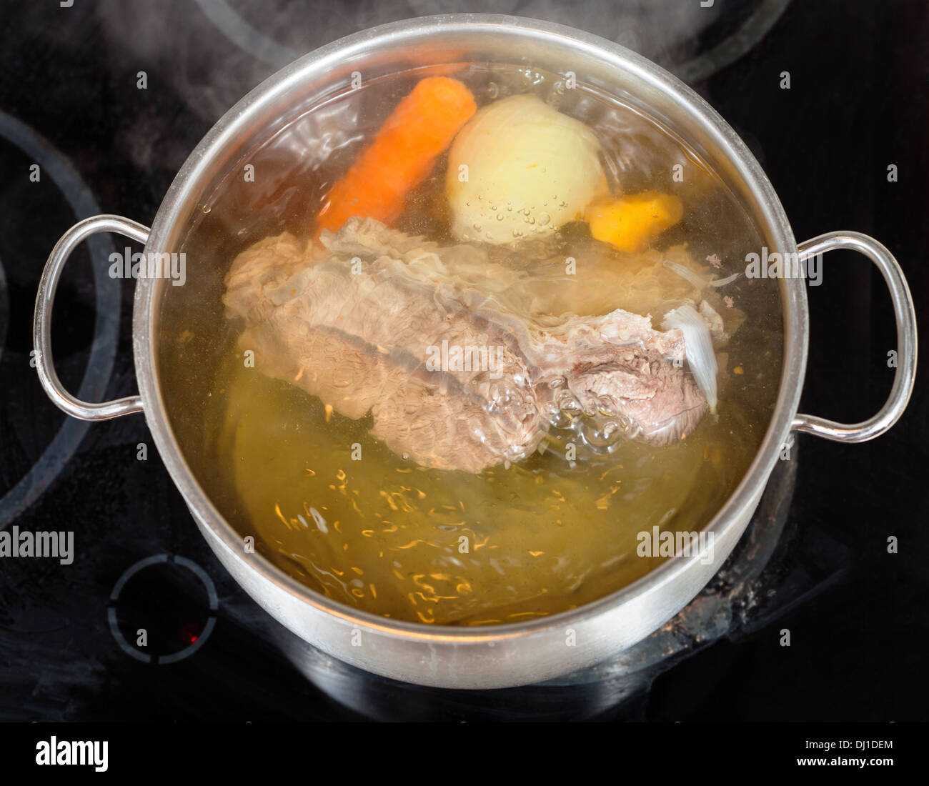 simmer of beef broth with seasoning vegetables in pan on glass ceramic cooker Stock Photo