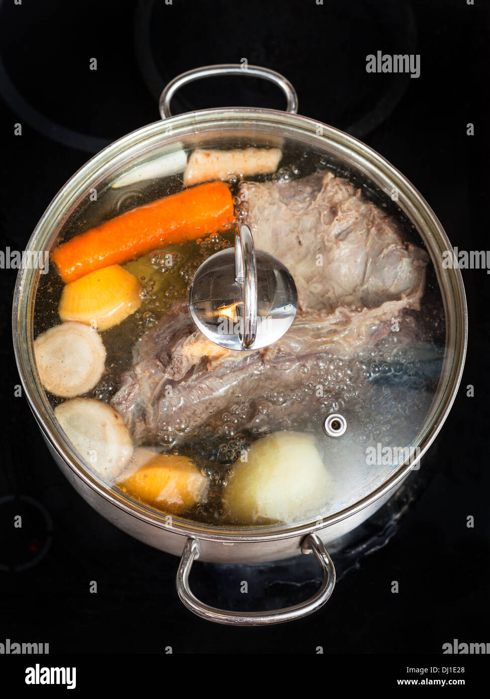 boiling of beef broth with seasoning vegetables in stew pan on glass ceramic cooker Stock Photo