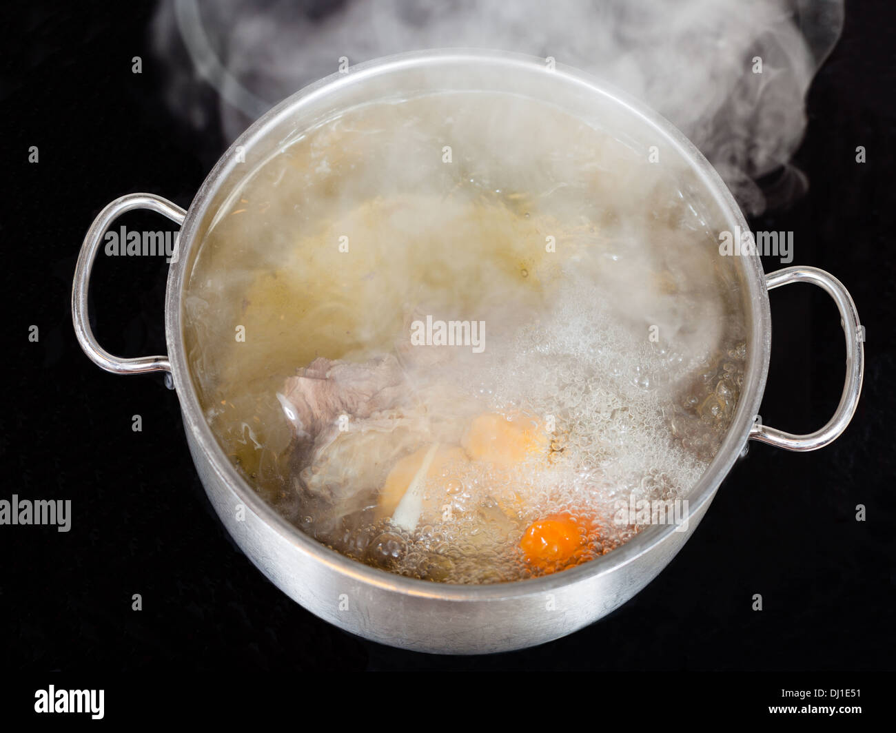 vapor over boiling of beef broth in pan on glass ceramic cooker Stock Photo