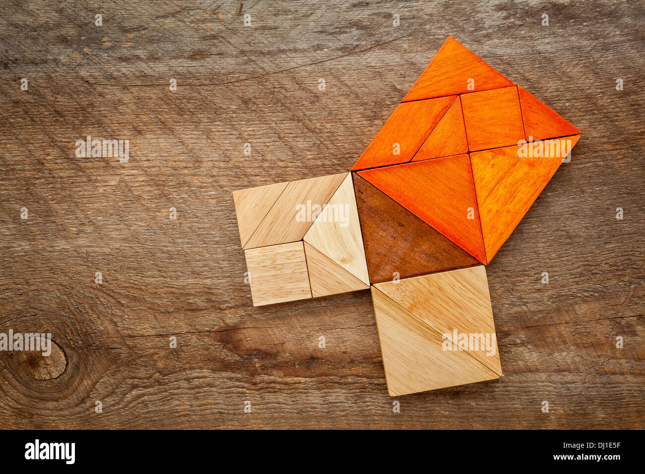 Pythagorean theorem illustrated with wooden pieces of tangram, a classic Chinese puzzle, against barn wood background Stock Photo