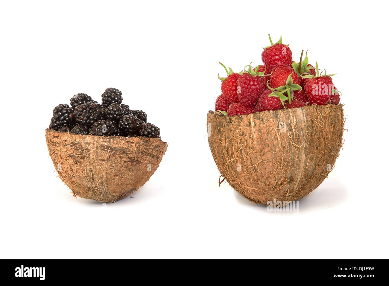 Raspberries and blackberries in a coconut shell isolated on white ...