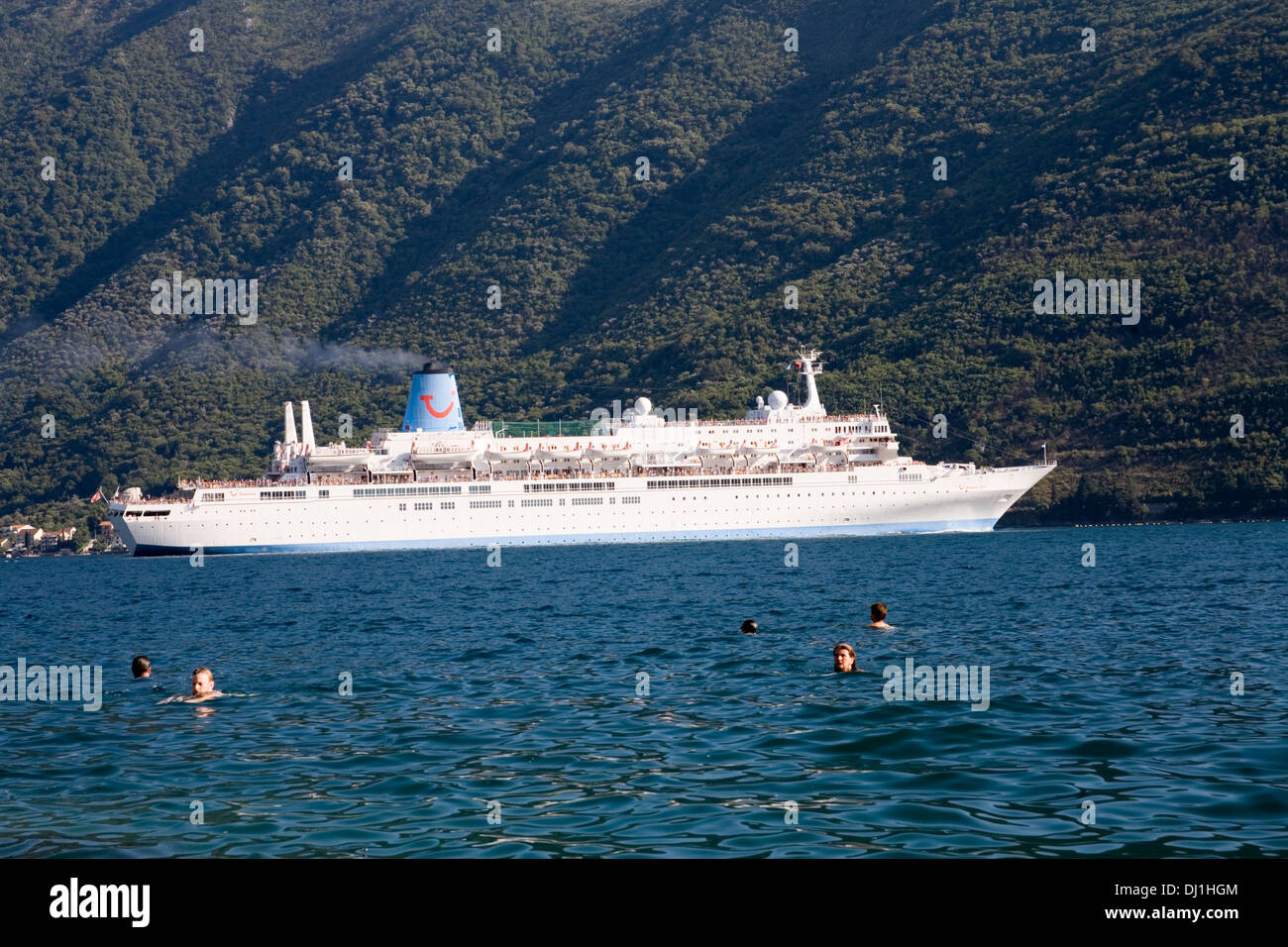 Thomson cruise liner ship leaving Bay of Kotor with people swimmimg in sea Stock Photo