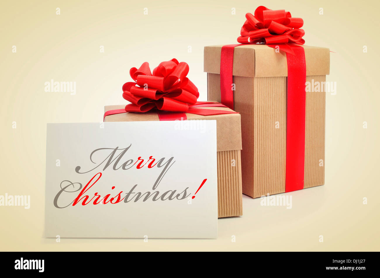 picture of some christmas gifts with red ribbon bows and a signboard with the sentence merry christmas written in it Stock Photo